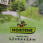 Arche de jardin décorative en métal couleur charbon, installée sur une allée, support pour plantes grimpantes.
